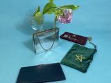 a glass vase with a flower in it next to a purse and a wallet