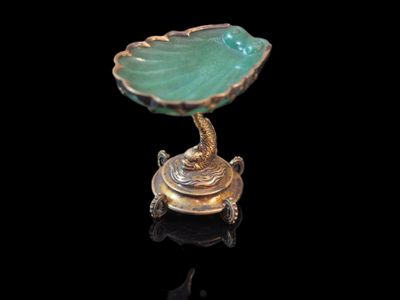 une assiette en or sur laquelle repose une feuille verte