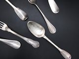five silver spoons and two silver spoons on a black table