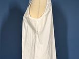 the back of a white top on a mannequin stand against a blue wall
