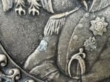 a close up of a silver plate with a picture of a man