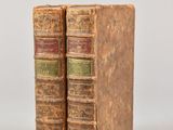 two old books sitting on top of each other on a white surface