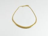 un collier en or posé sur une surface blanche