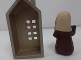 a small figurine of a person standing next to a small house