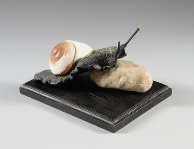statue représentant un escargot assis sur un rocher, un bâton dans la bouche