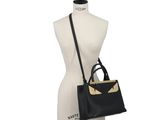 a black and gold handbag on a mannequin torso