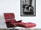 black and white photograph of a red chair and ottoman in a white room