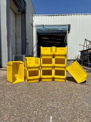 Plusieurs bacs jaunes sont empilés devant un immeuble