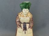 une figurine en céramique représentant une femme coiffée d'un chapeau vert