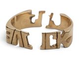 un gros plan d'une bague en or sur laquelle sont gravées des lettres