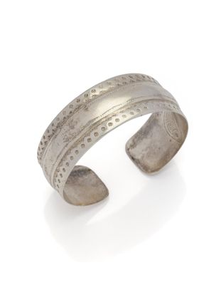un gros plan d'un bracelet manchette en argent sur fond blanc