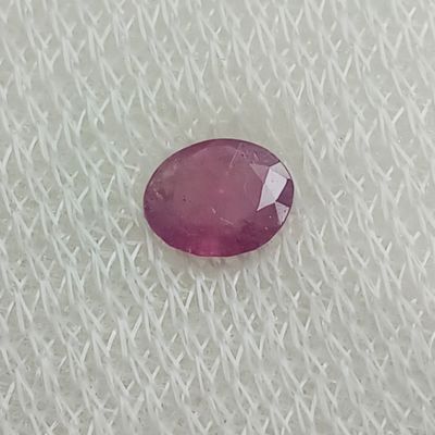 un gros plan d'un rubis rose de forme ovale posé sur un tissu blanc