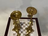 pair of brass candlesticks on a chess board on a stand