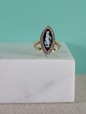 une bague en or sur laquelle est gravée la photo en noir et blanc du visage d'une femme