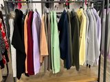 des vêtements suspendus à un portemanteau dans un magasin de vêtements, sur un sol en bois