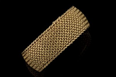 gros plan d'un bracelet en or sur fond noir