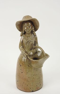 une figurine en céramique représentant une femme portant un chapeau et tenant un panier