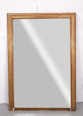 un grand miroir à cadre doré posé sur un mur de briques blanches