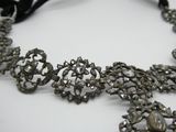 une image représentant un collier en argent orné d'un ruban noir sur un fond blanc
