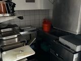 une petite cuisine équipée d'une cuisinière, d'un évier et d'une poubelle