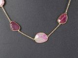 a necklace with pink stones and gold chains on a mannequin