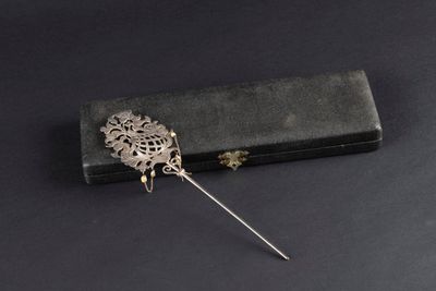 a close up of a metal pin with a flower on it