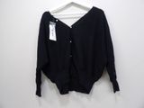 the black sweater is hanging on a hanger on a white wall