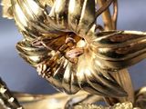 a close up of a gold plated flower on a branch