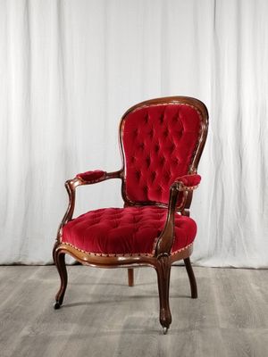 une chaise rouge posée sur un parquet, à côté d'un rideau blanc