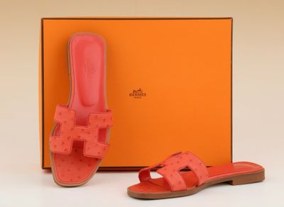a pair of pink sandals and an orange box on a white surface