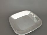 une assiette en argent posée sur une table grise, sur fond blanc