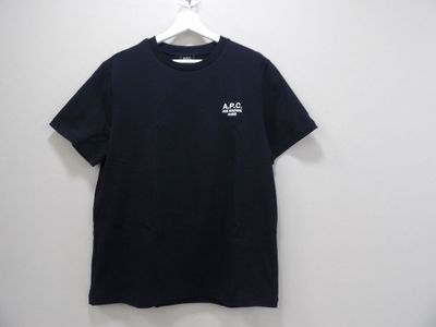 a black t - shirt hanging on a hanger against a white wall