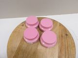 quatre bocaux roses posés sur une planche à découper en bois