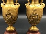 pair of antique brass vases on marble bases on a black background