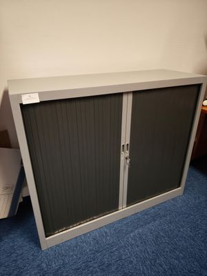 une armoire métallique à deux portes, avec un tiroir en dessous