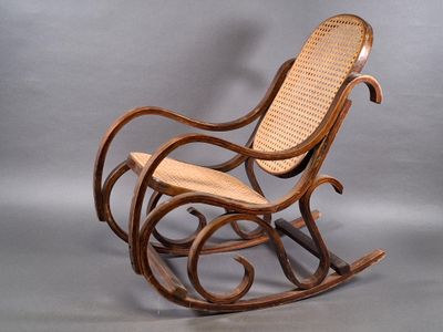 a wooden rocking chair with a wicker seat on a gray background