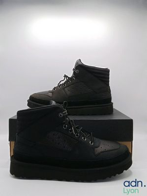 une paire de bottes noires pour homme posée sur une boîte noire