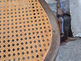 a wooden chair with a wicker seat on a sidewalk