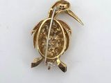 an image of a gold broochle with a bird on it