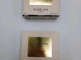 two boxes of guerlain cream sitting on top of a white table