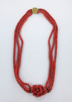 un gros plan sur un collier rouge orné d'une rose
