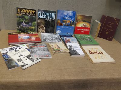 many books sitting on a table with a brown table cloth