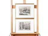 deux tableaux encadrés posés sur un chevalet en bois, sur un fond blanc