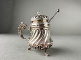an antique silver teapot with a handle on a table