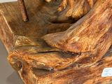 statue of a man holding a stick on a piece of wood