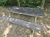 a picnic table with a bench in the middle of the grass