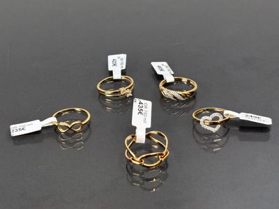 six paires de bagues en or munies d'étiquettes, posées sur une table
