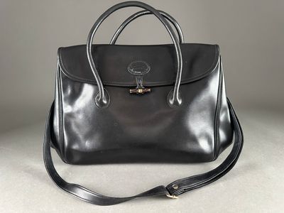 un gros plan d'un sac à main noir posé sur une surface blanche