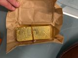 a person holding a piece of gold in a brown paper bag