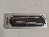 a metal object on a white surface with a black handle